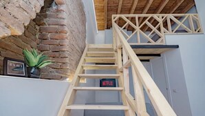 A wooden staircase with a handrail, a brick wall, a potted plant, and a sign with 'NETFLIX' on it. - Clit1: Bright Loft Near Loreto (Milano)