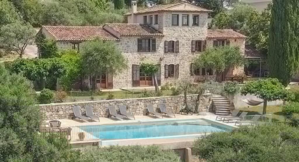 Una villa de piedra con piscina, rodeada de vegetación.