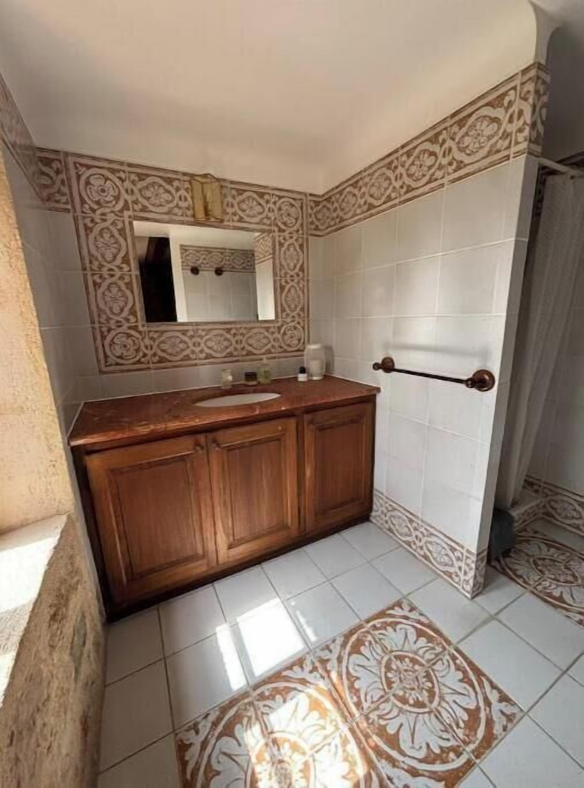 A bathroom with patterned tiles, a wooden vanity, and a towel rack.