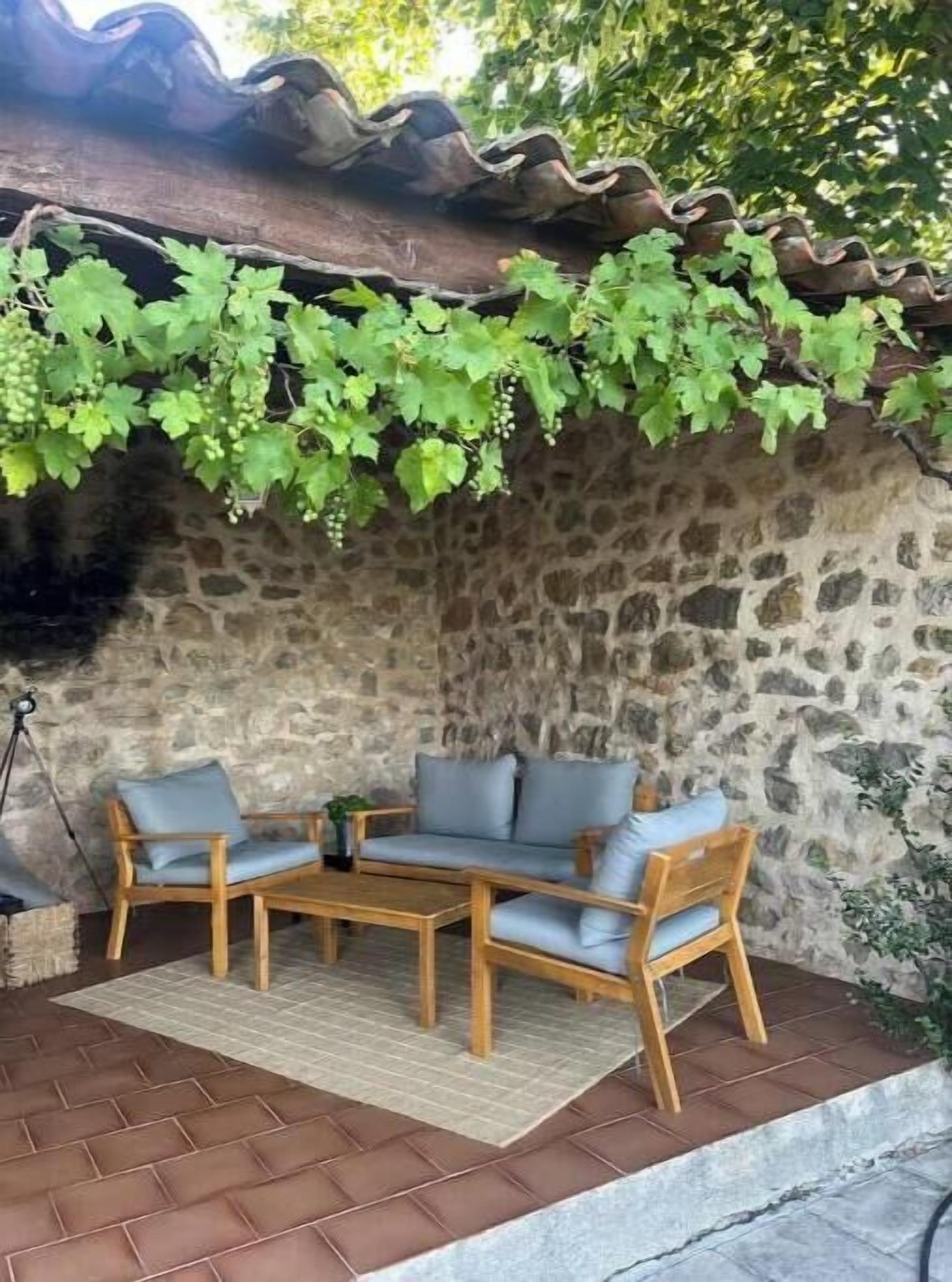 A stone wall with a curved roof, a wooden bench, and a table with chairs.