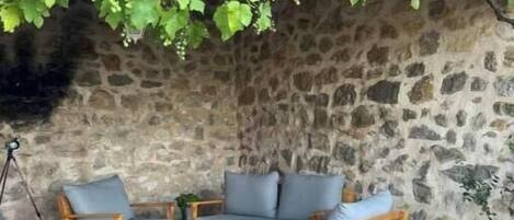 A stone wall with a curved roof, a wooden bench, and a table with chairs.