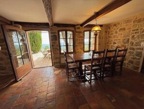 A rustic dining area with a stone wall, wooden table, and chairs.