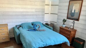 A bedroom with a bed, wooden floor, dresser, nightstand, and a framed picture on the wall. - Bright studio apartment with a small terrace (Viroflay)