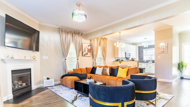 Ein Wohnzimmer mit Ecksofa, Kamin, Wandfernseher und einer Kronleuchter.