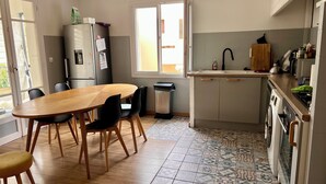 Une cuisine compacte comprenant un coin repas, un réfrigérateur, une poubelle et une fenêtre.