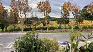 Une intersection où deux routes se croisent, bordée d’arbres et d’un mur de pierre.