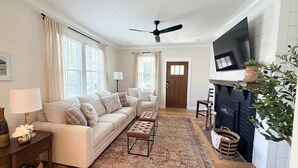 Una sala de estar con sofá, reposapiés, lámpara de pie y chimenea.