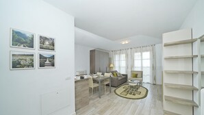 A modern living room with a dining area, a sofa, a coffee table, and a bookshelf. - Corte Fasanella 3 in Toscolano-maderno (Toscolano Maderno)