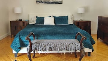 A bedroom with a bed, nightstands, a ceiling fan, a window, and a painting on the wall.