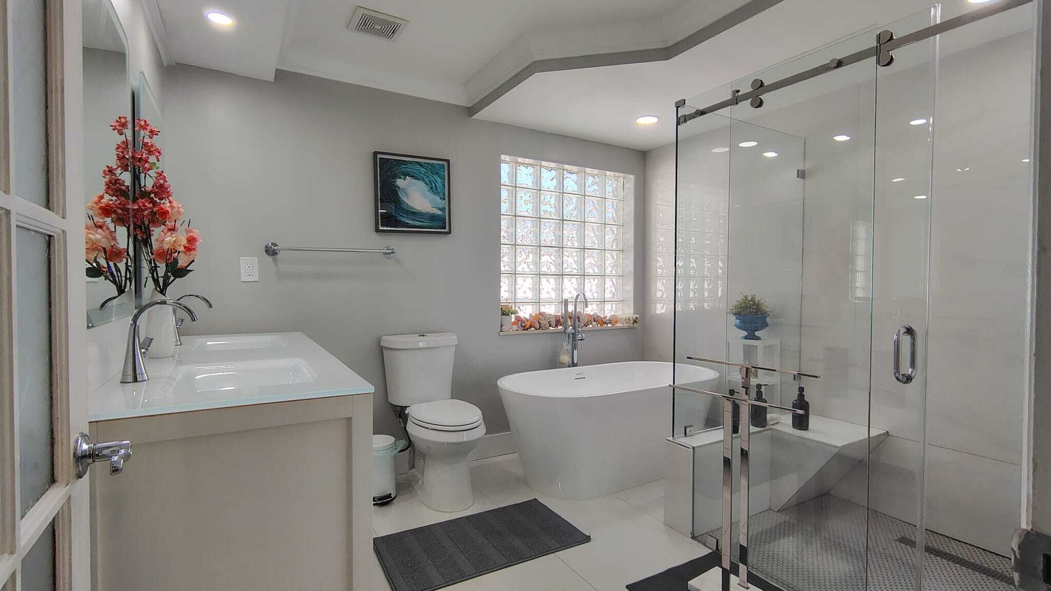A modern bathroom with a glass shower enclosure, a freestanding bathtub, a toilet, and a sink.