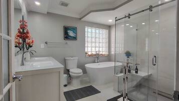 A modern bathroom with a glass shower enclosure, a freestanding bathtub, a toilet, and a sink.
