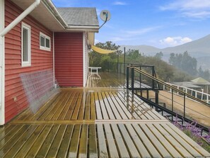 A red building with a wooden deck, a satellite dish, and a view of distant mountains.