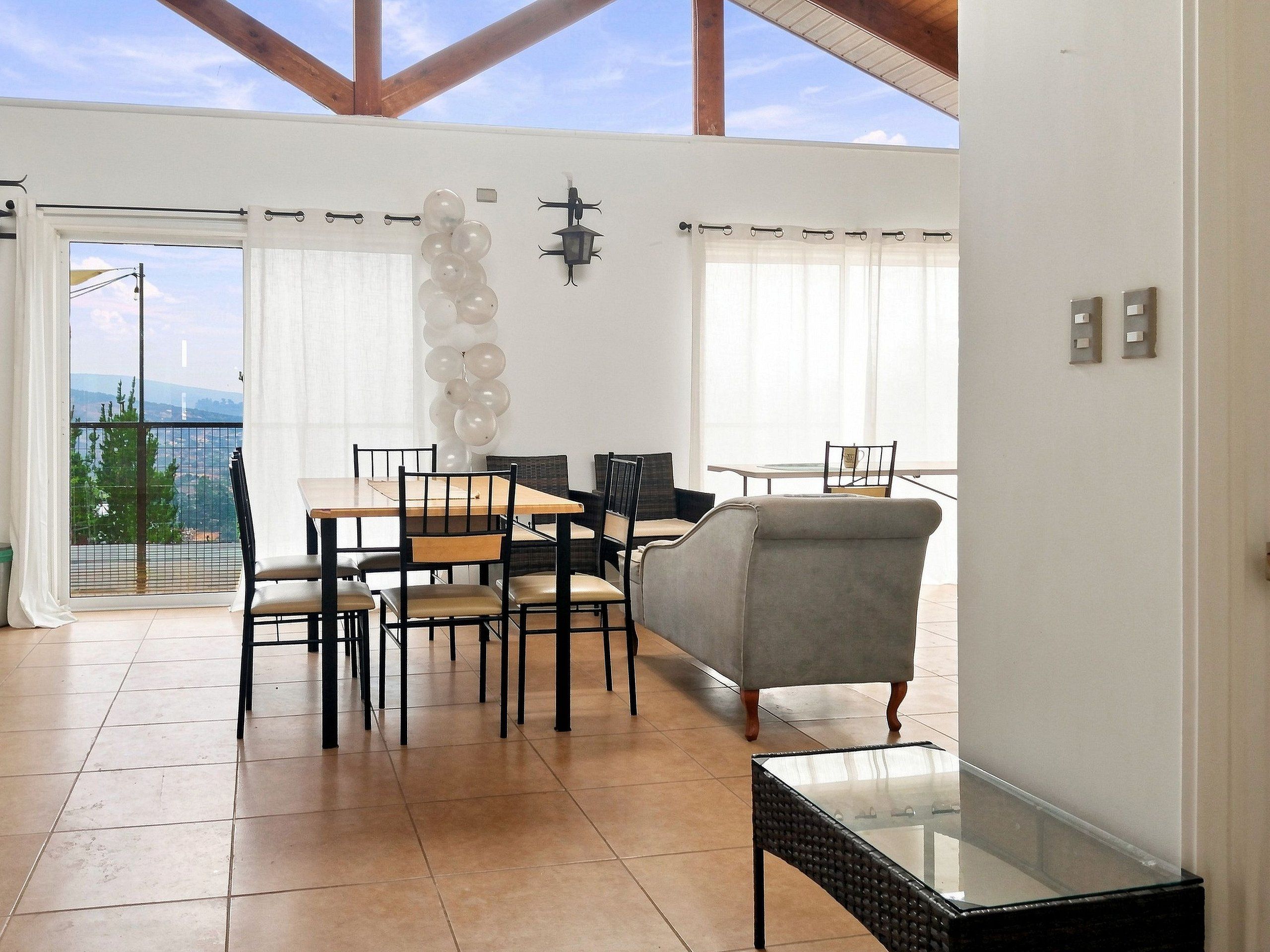 Un comedor con mesa y sillas, un sofá, y un balcón con vistas.