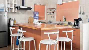 Una cucina con isola centrale, sgabelli da bar, frigorifero e dispenser per acqua.