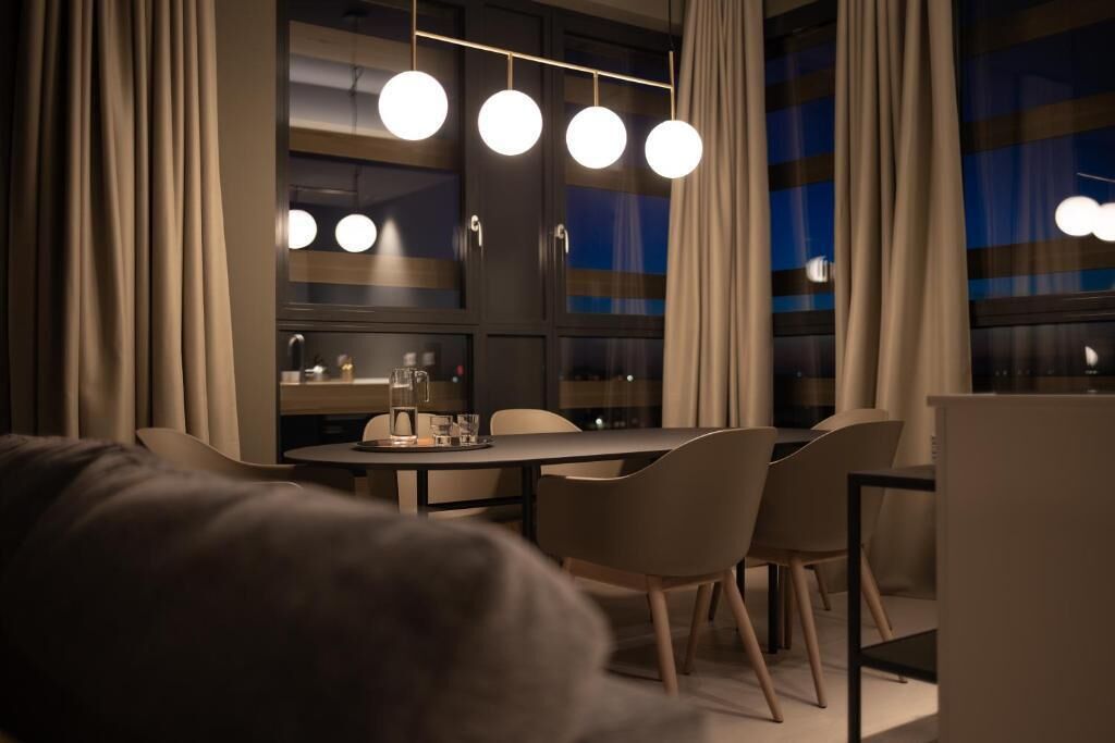 A modern dining area with a table, chairs, and pendant lights.