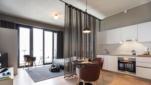 A modern apartment with a dining area, kitchen, and a large window. - Aurum ApartHotels Città Studi (Milano)