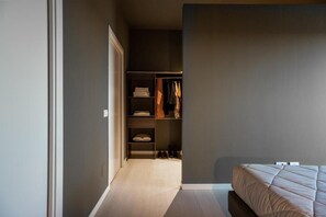 Un dormitorio con una cama, un armario con estantes y una puerta que da a otra habitación.