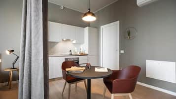 Uma cozinha moderna com armários brancos, uma mesa de jantar com duas cadeiras e uma luminária pendente.