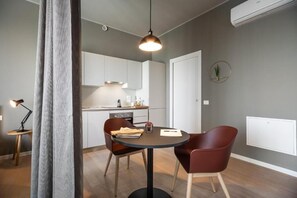 Una cocina moderna con armarios blancos, una mesa de comedor con dos sillas y una lámpara colgante.