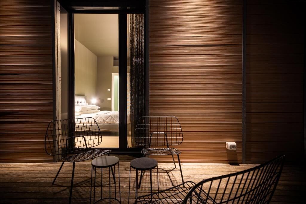 A modern room with a bed, two chairs, and a small table.