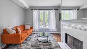 A living room with a sofa, a glass coffee table, and a fireplace. - Pristine Chicago Home - 3BD - 2BA - Free Parking - 2 (Chicago)