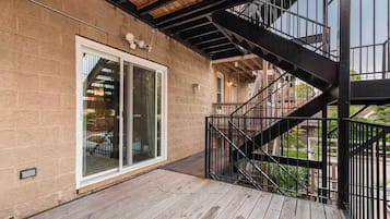 A wooden deck with a metal staircase leading to a balcony.