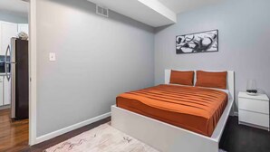 A bedroom with a bed, a nightstand, a wall art piece, and a door leading to a kitchen. - Pristine Chicago Home - 3BD - 2BA - Free Parking - 2 (Chicago)