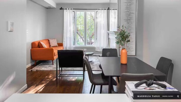 A modern living room with a sofa, a dining table with chairs, a coffee table, and a bookshelf. - Pristine Chicago Home - 3BD - 2BA - Free Parking - 2 (Chicago)
