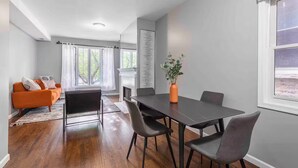 A modern living room with a fireplace, a dining area with a table and chairs, and a sofa. - Pristine Chicago Home - 3BD - 2BA - Free Parking - 2 (Chicago)