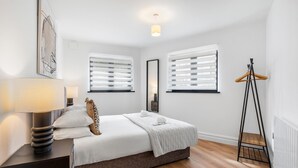 A bedroom with a bed, bedside tables, a hanging light fixture, a mirror, and a radiator. - Urban Shore | By My Getaways (Brighton)