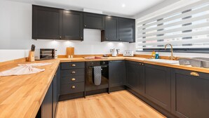 A modern kitchen with dark cabinets, wooden countertops, and a built-in oven. - Urban Shore | By My Getaways (Brighton)