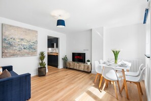 Un salon moderne avec un téléviseur, un coin repas et un grand tableau abstrait.