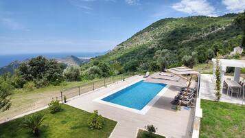 A swimming pool with a view of the sea and hills.