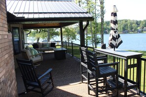 Un espace extérieur aménagé, abrité et doté de sièges, avec vue sur un lac, comprenant des chaises et un canapé.