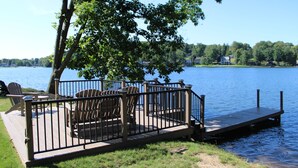 Järvenrantaterassi, jossa on Adirondack-tyylisiä tuoleja ja laituri, joka ulottuu veteen.