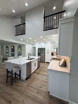 A spacious kitchen with a central island, upper-level seating, and a modern design. - Spectacular Million-Dollar Lake Front 5 Bedroom Home! Large yard deck & dock! (DuBois)
