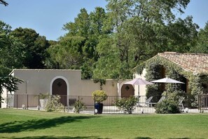 A building with a tiled roof, arched windows, and a fenced courtyard. - Mas Saint Jean - Domaine de Malaga - New Property (Maussane-les-Alpilles)