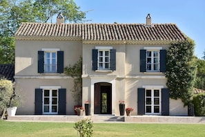 A two-story house with a tiled roof, a central entrance, and a small porch with potted plants. - Mas Saint Jean - Domaine de Malaga - New Porperty (Maussane-les-Alpilles)