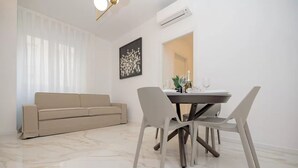 Un salon moderne avec un canapé beige, une table à manger avec des chaises et un sol en marbre.