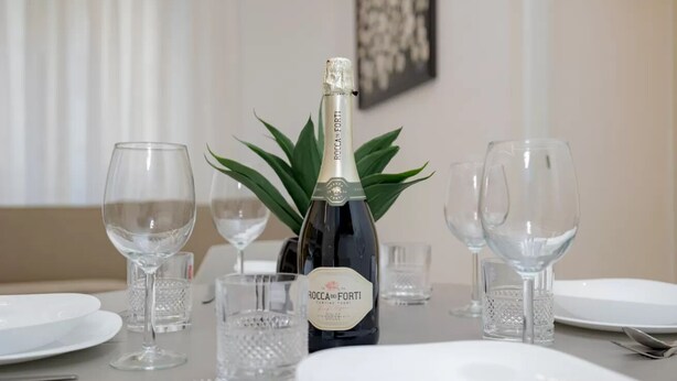 Une table mise pour le dîner, avec une bouteille de vin, des verres et des assiettes.