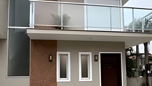 A modern two-story house with a balcony, large windows, and a garage. - Diamond Riviera - Casa Nova a 30m da Praia da Ferrugem (Garopaba)