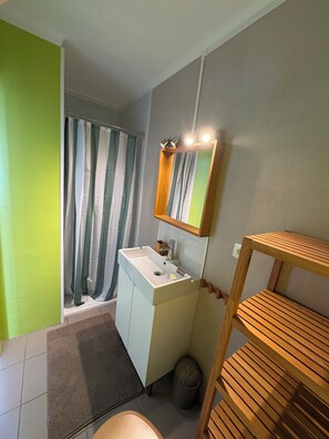 Ein Badezimmer mit Waschbecken, Spiegel, Duschvorhang und einem Holzboden.