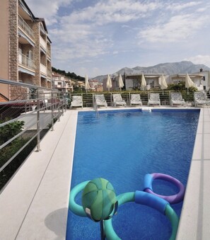 A swimming pool with lounge chairs and a view of mountains. - A6 - Spacious apt w Pool, Terrace and sea View (Dugi Rat)