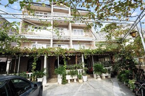 A multi-story building with balconies, potted plants, and a car parked in front. - A6 - Spacious apt w Pool, Terrace and sea View (Dugi Rat)