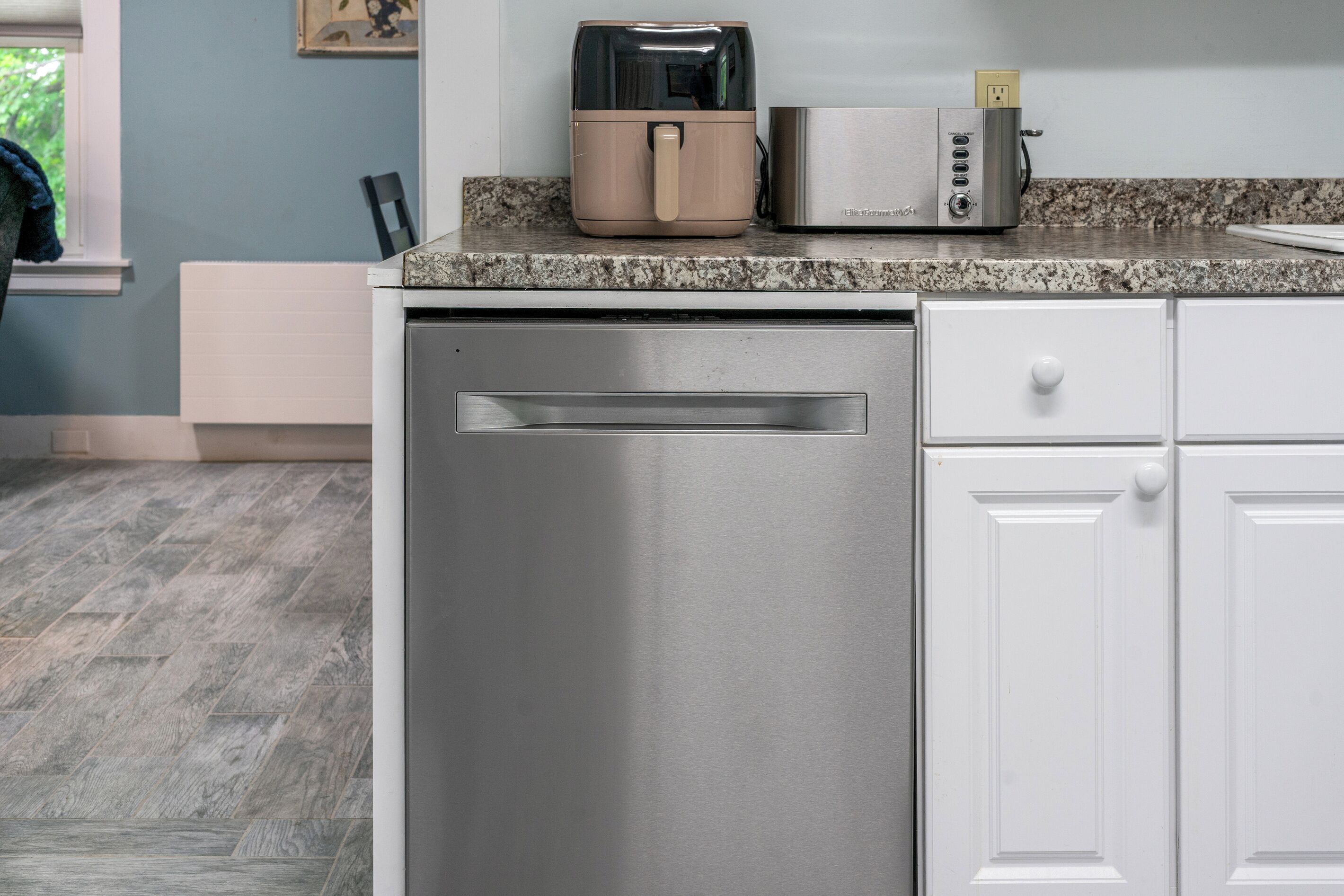 A kitchen with a dishwasher, a toaster, and a coffee maker on the countertop.