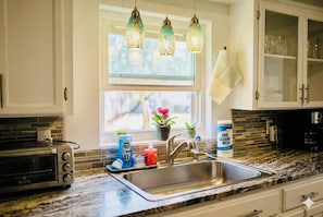 A kitchen with a built-in toaster, a sink with a faucet, and a window with hanging lights. - Summer Escape .Heated Pool + Game Room & Sleeps 10 (Altamonte Springs)