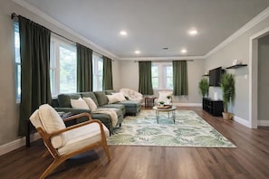 A living room with a sectional sofa, a wooden chair, a coffee table, and a patterned rug. - Summer Escape .Heated Pool + Game Room & Sleeps 10 (Altamonte Springs)