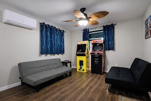 A room with a grey sofa, a black sofa, a ceiling fan, and a vending machine. - Summer Escape .Heated Pool + Game Room & Sleeps 10 (Altamonte Springs)