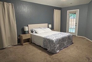 A bedroom with a bed, nightstand, and a door to a balcony. - Quiet, Clean, and Cozy: The Stonecrest House! (Abilene)