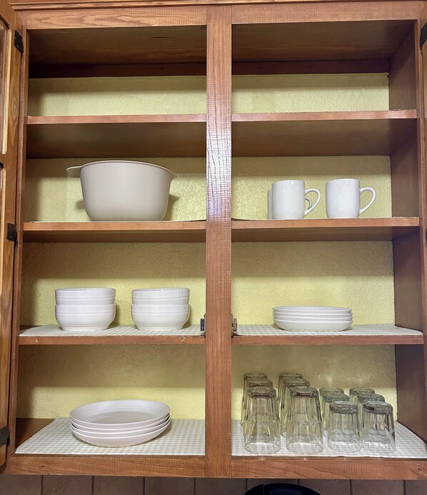 A wooden cabinet with multiple shelves containing white bowls, plates, and glassware. - Quiet, Clean, and Cozy: The Stonecrest House! (Abilene)